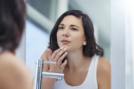 Mujer revisando su piel en el espejo 